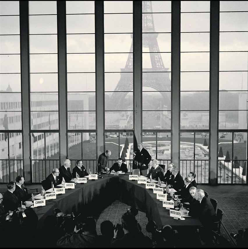 Réunion du Conseil de l'Atlantique Nord au palais de Chaillot à Paris, la tour Eiffel visible derrière les grandes baies vitrées